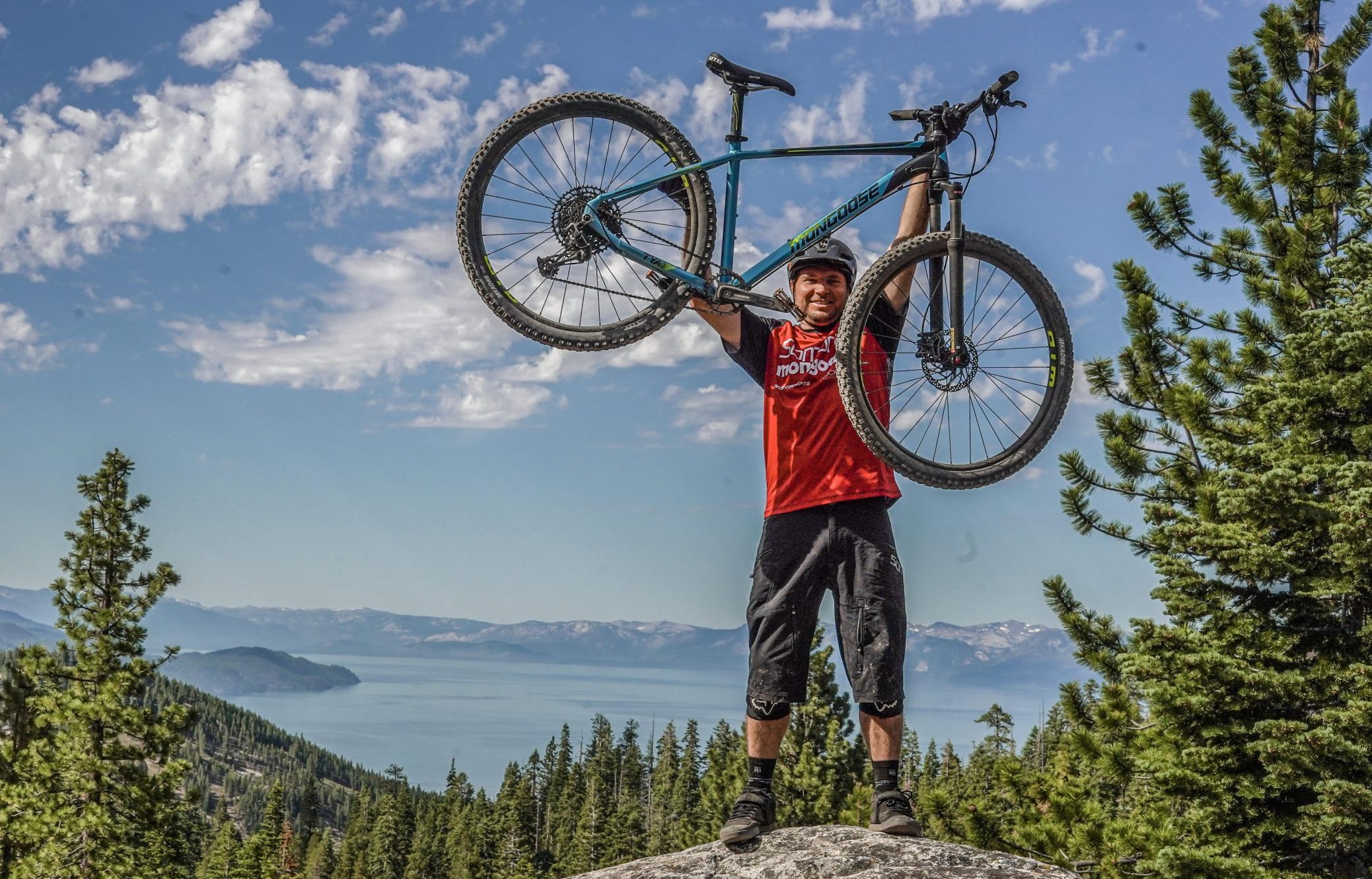 Man som håller upp sin Cannondale mountainbike i skogen